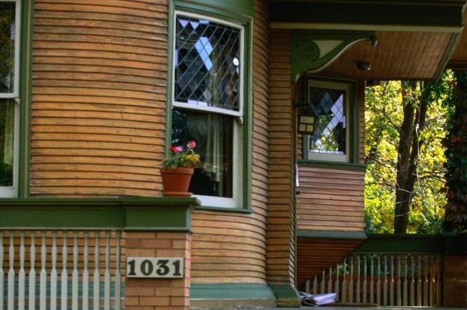 Детайл от затворена веранда на къщата, сайдинг от естествено дърво със зелена облицовка, двойно окачени оловни прозорци, декоративни корбели