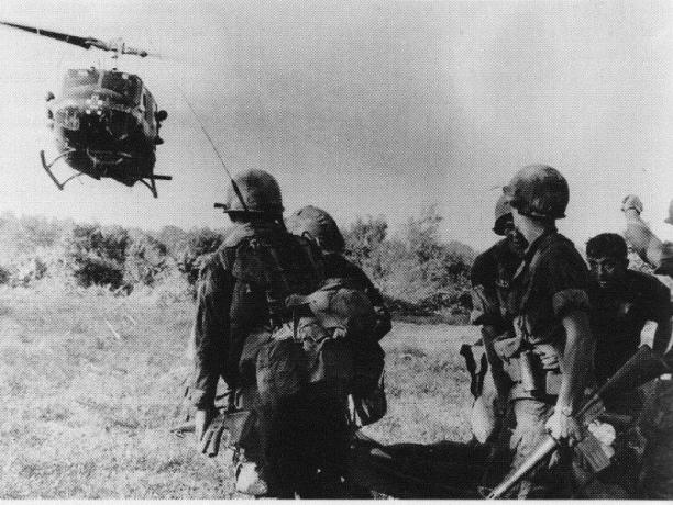 Хеликоптер UH-1 Huey каца близо до група войници.