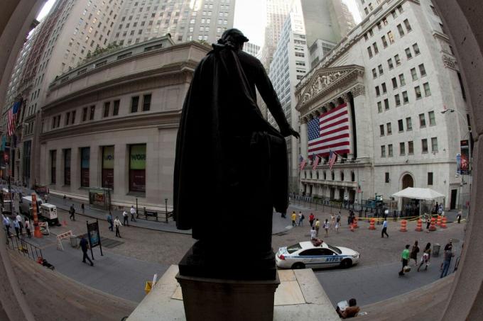 Зад огромно американско знаме, покриващо колонадата, фасадата на Нюйоркската фондова борса се наблюдава от статуя на Джордж Вашингтон на Уолстрийт.