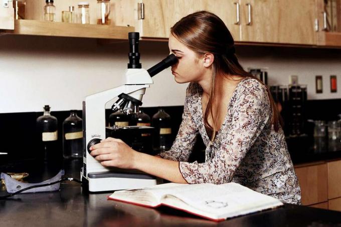Тийнейджърка (14-16 г.) с помощта на микроскопи в клас по научна лаборатория