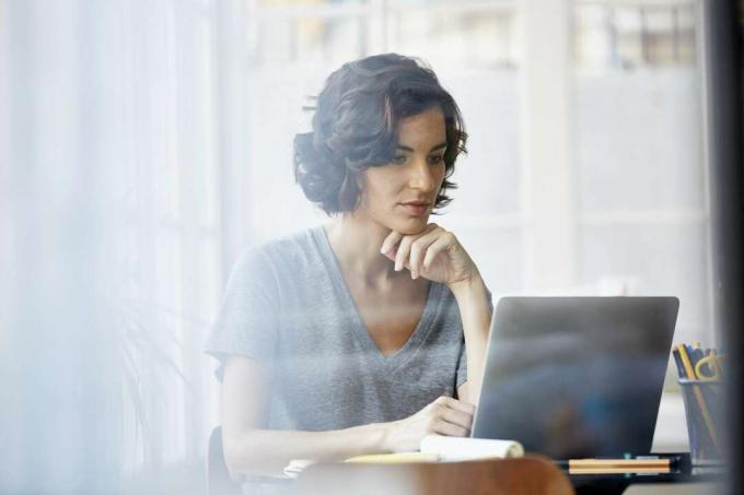 Mujer verificando información en computadora portátil.