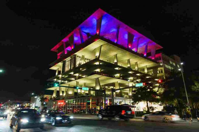 нощен изглед на гараж на няколко нива, осветен с лилави светлини на последния етаж