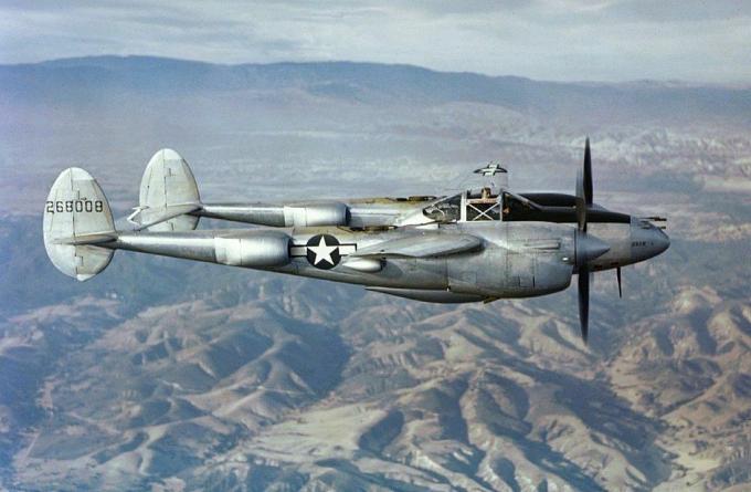 Сребърен изтребител от Мълния P-38, летящ над планини