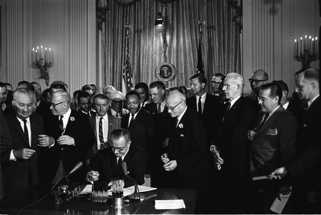 Президентът Линдън Б. Джонсън подписва Закона за гражданските права от 1964 г. като Мартин Лутър Кинг, младши, и други, гледайте.