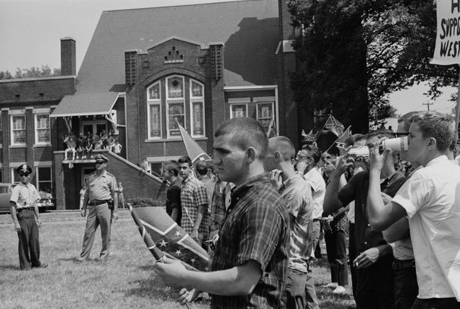 Тълпа ученици в гимназията Woodlawn в Бирмингам, Алабама, развяващи знамето на Конфедерацията в противовес на началото на Бирмингамската кампания, май 1963 г.