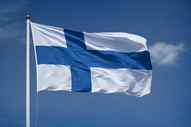 Вдигнат финландски флаг с фон на синьо небе